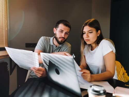 young couple manages finances by looking through their bank accounts in the living room
